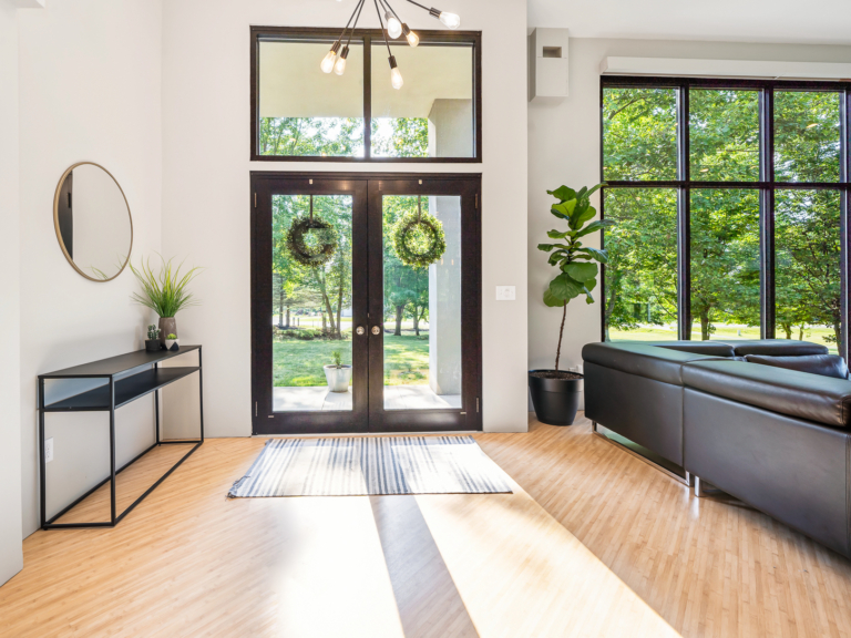 Open window front door of modern renovation home project by The RBT Group which has crisp lines, natural wood flooring, and floor-to-ceiling windows.