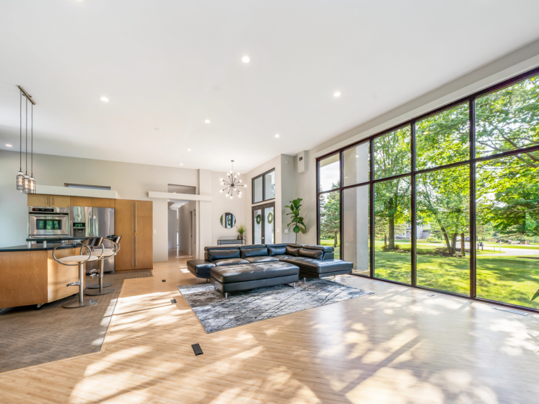 Open floor plan with floor-to-ceiling windows and natural elements of the living space and kitchen of modern renovation home project by The RBT Group.